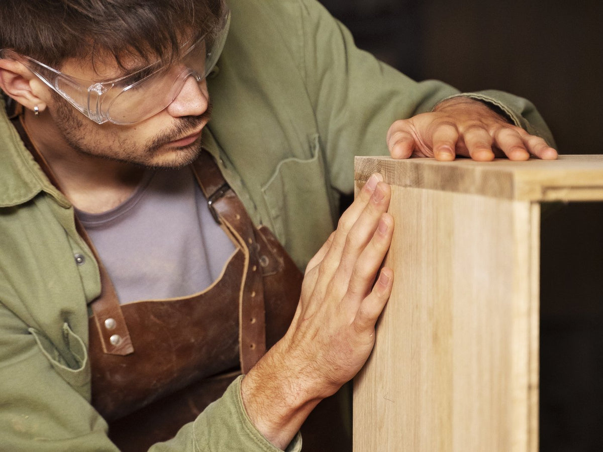 Craftsman checking the corner joint and surface of a cabinet carcass by hand before shipment